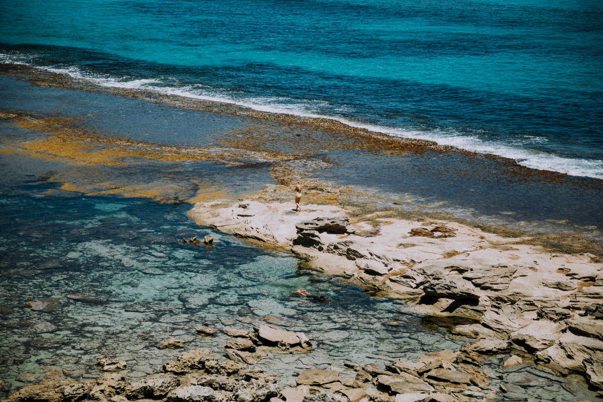 Girl walking along rocks at the beach